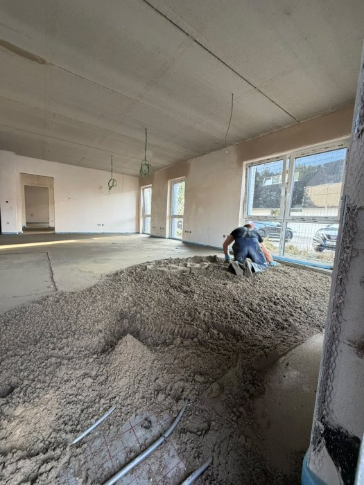 Hoffmann-Bau-Handwerker verteilt frischen Zementestrich im Rohbau