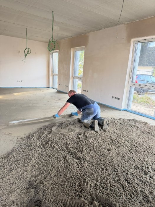 Hoffmann-Bau-Handwerker zieht frischen Zementestrich mit der Latte ab
