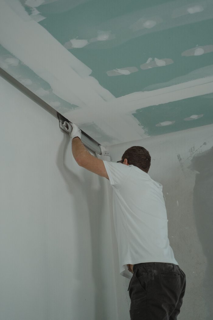 Handwerker spachtelt die Kante zwischen Wand und Decke